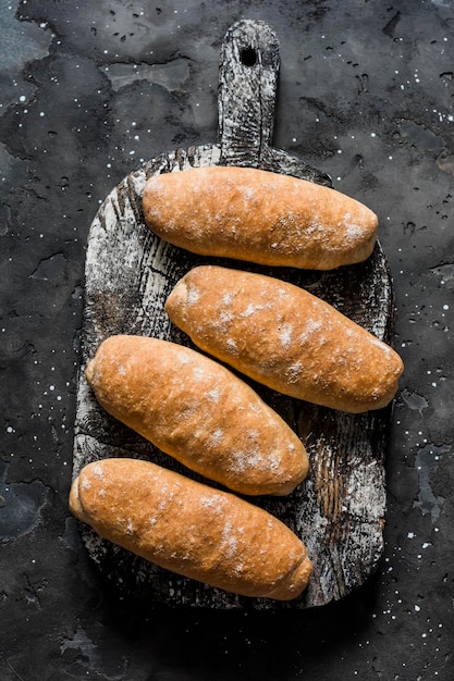 Petits pains de grains entiers faits maison pour sandwichs hot-dogs sur une vue de dessus de planche à découper rustique