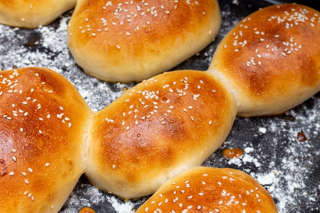 Petits pains à hamburger avec des graines de sésame sur une plaque à pâtisserie