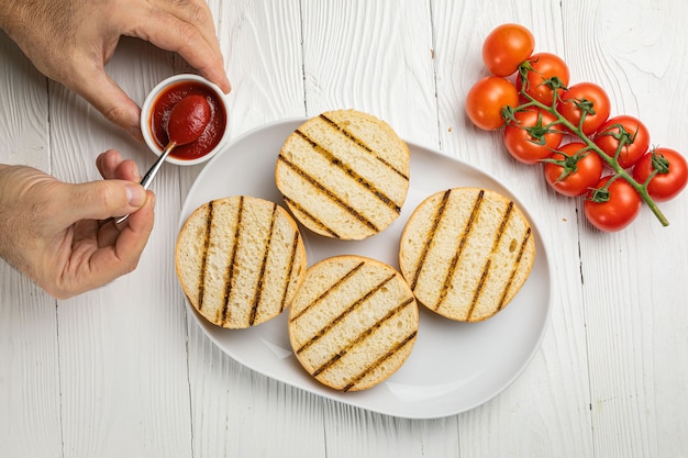 Petits pains à hamburger sur une plaque blanche. Table en bois blanc