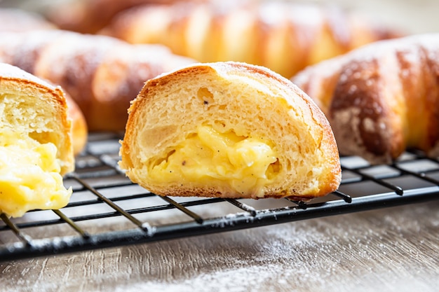 Petits pains à la levure faits maison avec garniture à la crème avec du sucre en poudre. Petits pains avec patisier à la crème vanille.