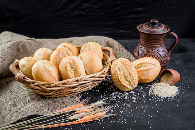 Petits pains savoureux sucrés dans le panier sur fond de bois noir