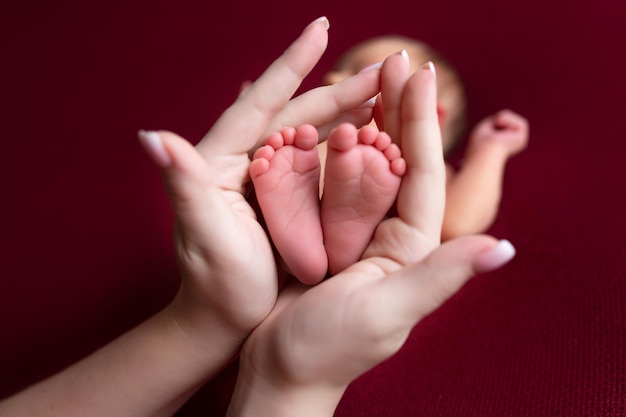 petits pieds d'un nouveau-né dans les mains de sa mère