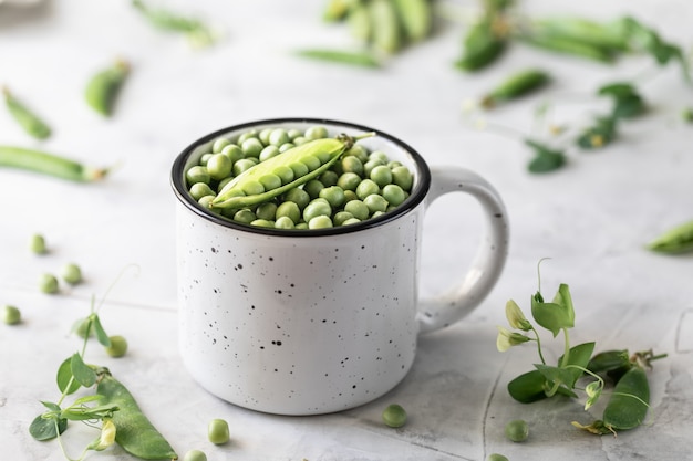 Petits pois verts dans une casserole sur blanc