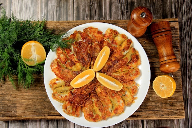 Petits poissons frits sur une assiette, décorés de tranches de citron