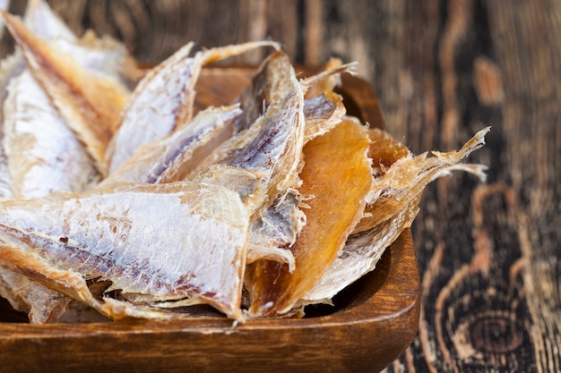 Petits poissons séchés et dépecés sur une table en bois, petits poissons éviscérés et séchés au sel