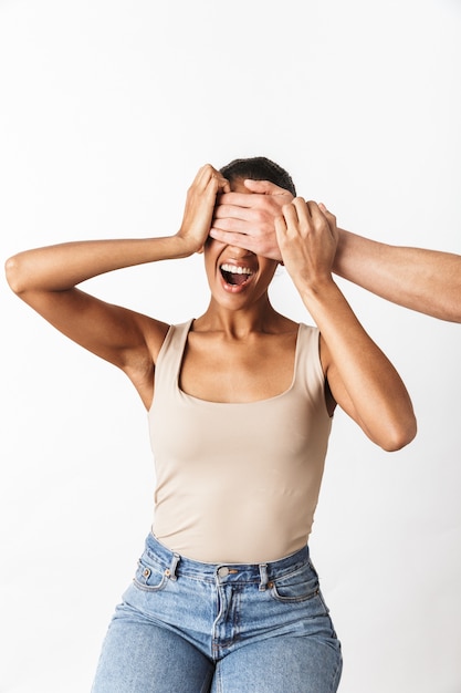 Peur crier jeune femme africaine assise tandis que la main de l'homme coning ses yeux isolés sur blanc