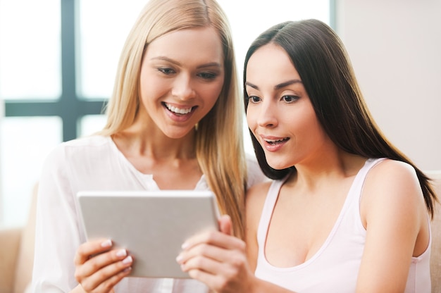 Peux-tu le croire?! deux belles jeunes femmes regardant la tablette numérique et ayant l'air surpris