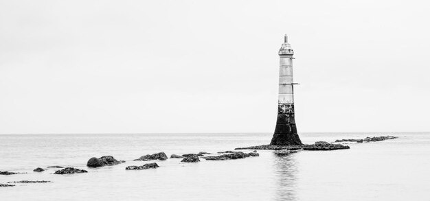 Photo un phare au milieu de la mer contre le ciel