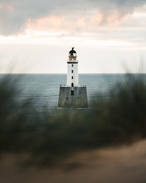 Phare sur le bâtiment par la mer contre le ciel