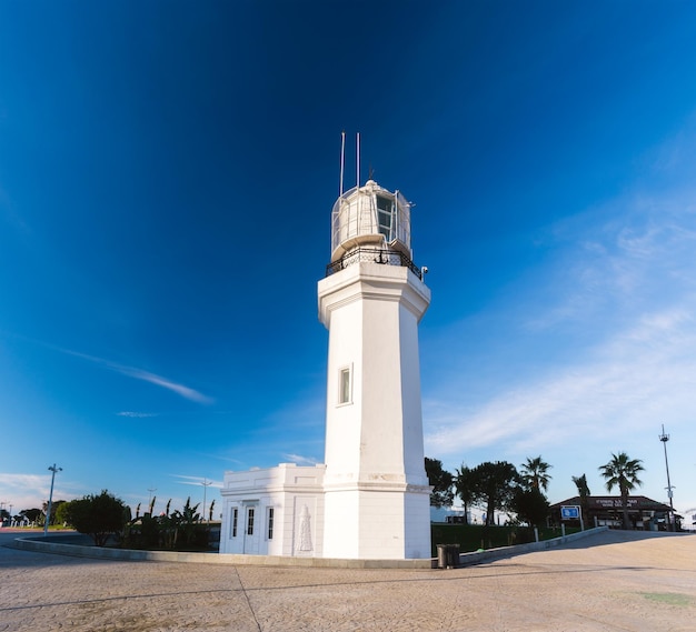 un phare blanc avec un ciel bleu et des palmiers en arrière-plan