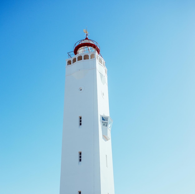 phare blanc sur fond de ciel bleu près de la mer