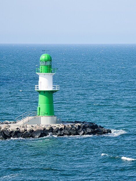 Phare blanc vert sur la rivière Warnow à Rostock Vagues sur le bord de pierre