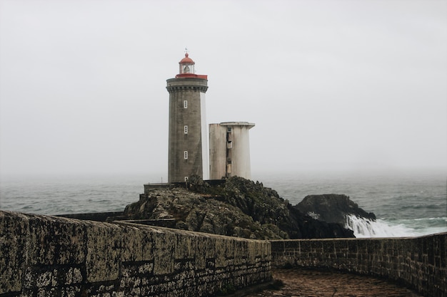 Phare sur le corps de la mer un jour sombre