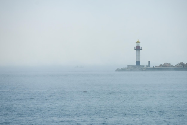 Phare dans une mer brumeuse au lever du soleil