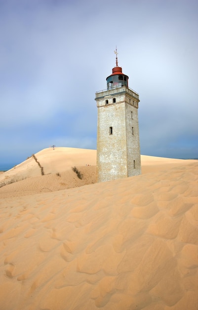 Phare sur une dune de sable au bord de la mer contre un ciel bleu Vieille tour mystérieuse seule dans le désert Phare déserté isolé sur du sable beige Scène de nature paisible et tranquille dans le Jutland au Danemark