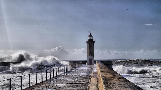 Phare sur la jetée en mer contre le ciel