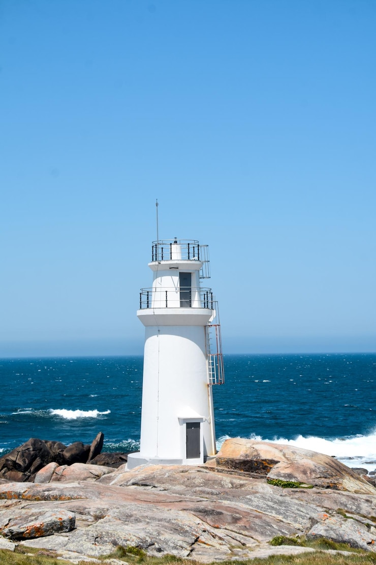 Photo un phare sur la mer contre un ciel bleu clair