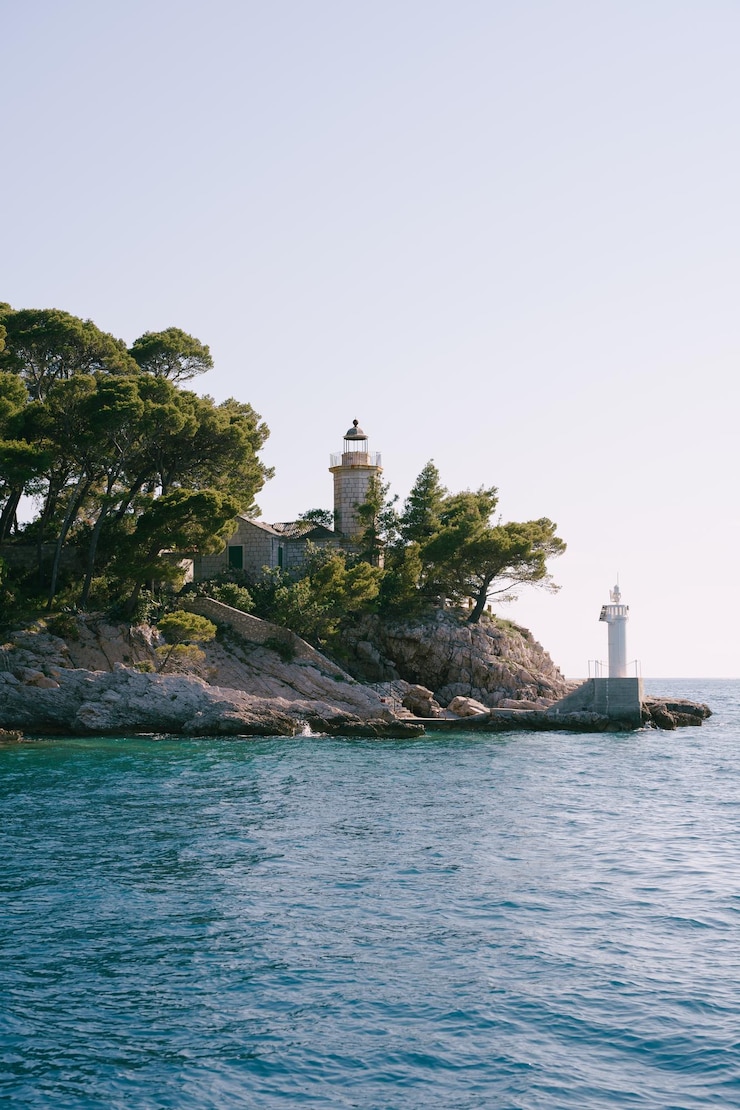 Photo le phare par la mer et les bâtiments contre un ciel clair