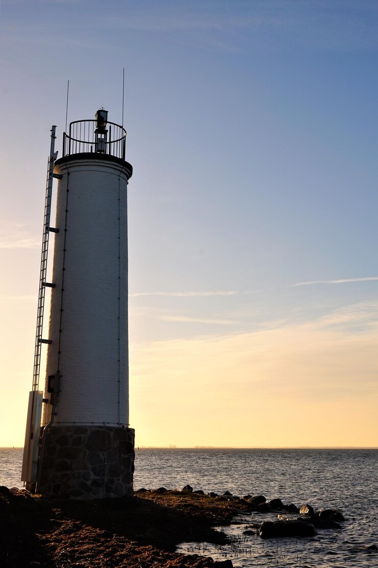 Photo phare par la mer contre le ciel au coucher du soleil