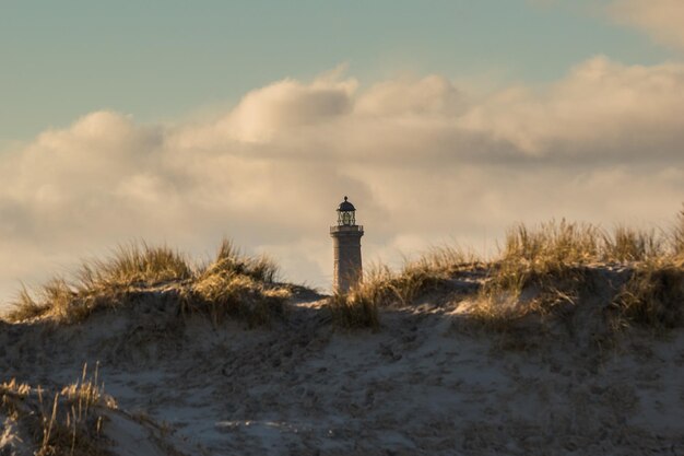 Phare par la mer contre le ciel au coucher du soleil