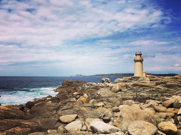 Un phare par la mer contre un ciel nuageux