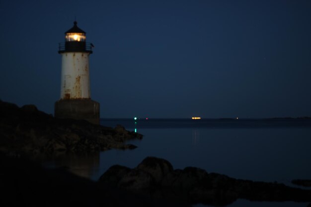 Photo phare par la mer contre le ciel la nuit