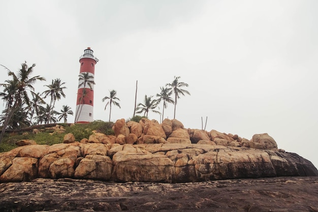 Phare sur la plage au ciel dramatique du matin à Kovalam Kerala Inde