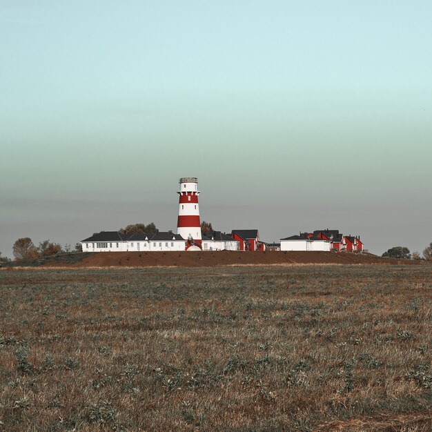 Phare rouge et blanc et bâtiments vus du terrain.