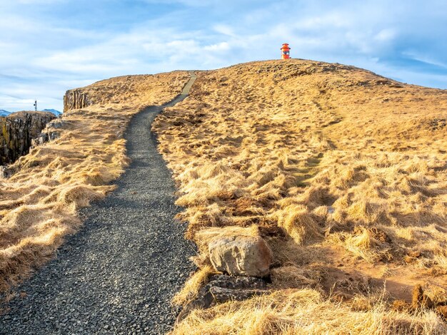 Phare de Stykkisholmur sur la colline avec le pré jaune sous le ciel bleu nuageux en Islande