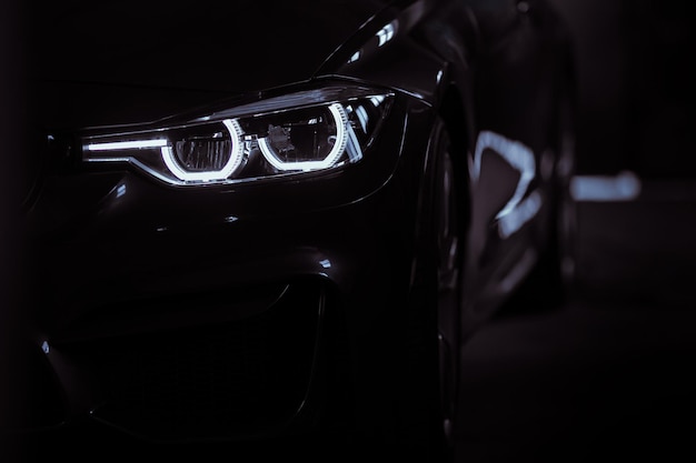 Photo phares de voitures modernes noires vue avant silhouette d'une voiture de sport noire avec phares de près