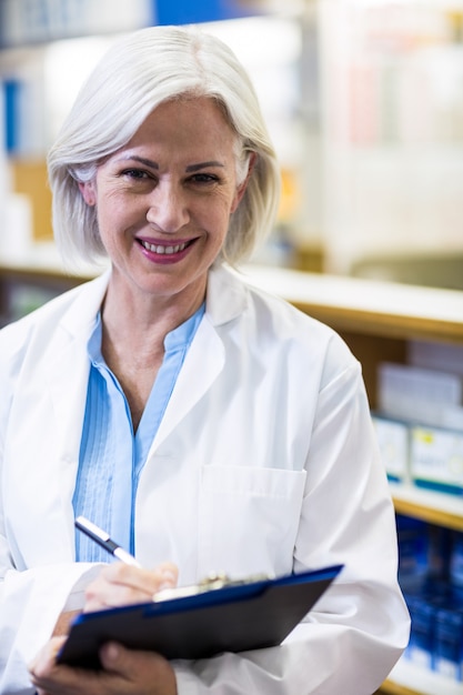 Pharmacien écrit sur presse-papiers en pharmacie