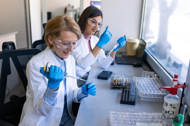 Pharmacien pipetant des fluides dans une bouteille dans le département de recherche de l'industrie pharmaceutique Scientifique ou chercheur médical tenant un tube à essai et laissant tomber un réactif dans le laboratoire de biochimie