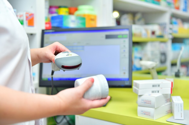 Pharmacien scannant le code-barres d'un médicament dans une pharmacie