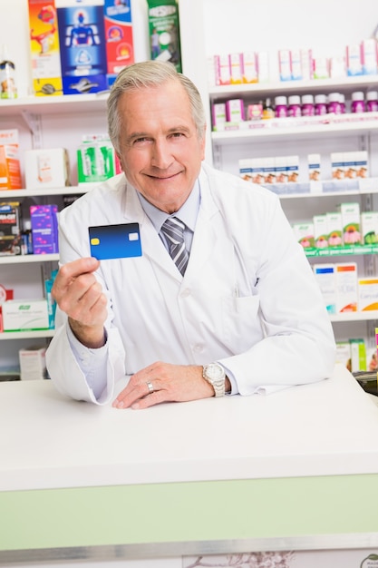 Pharmacien senior souriant tenant la carte de crédit