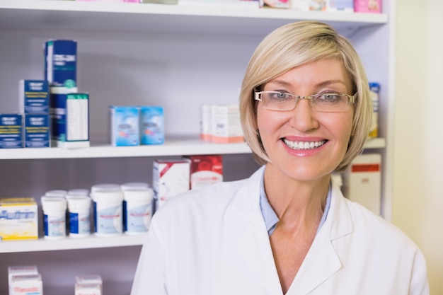 Pharmacien souriant en blouse de laboratoire en regardant la caméra