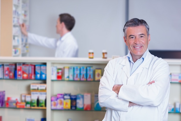 Pharmacien souriant debout avec les bras croisés