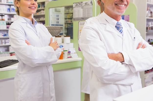 Pharmacien souriant et son stagiaire avec les bras croisés