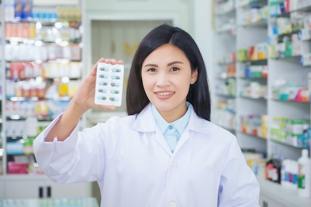 Le pharmacien tient un paquet de pilules dans ses mains.