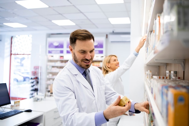 Pharmacien travaillant dans un magasin de pharmacie et organisant des boîtes de médicaments sur l'étagère.