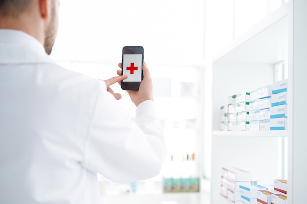 Pharmacien utilisant un smartphone dans sa pharmacie