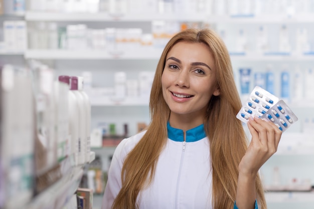 Pharmacienne attrayante offrant un pack de jeunes vitamines, copie espace