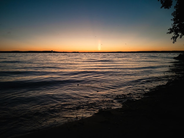 Phénomène atmosphérique colonne de soleilCoucher de soleil sur le lac Paysage d'été en soirée