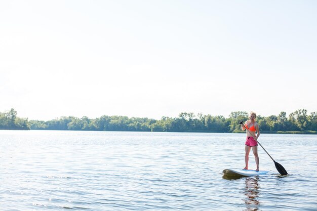 Photo d'action d'une jeune femme sur une planche à pagaie