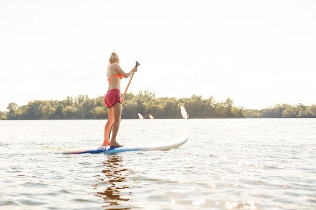 Photo d'action d'une jeune femme sur une planche à pagaie