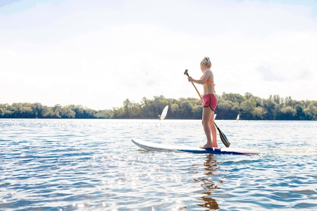 Photo d'action d'une jeune femme sur une planche à pagaie