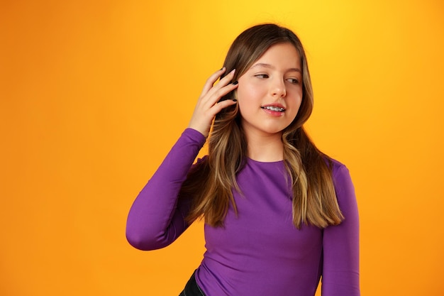 Photo d'une adolescente souriante, portrait sur fond jaune en studio