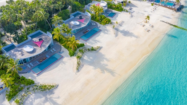 Photo aérienne de belles piscines de villas de plage tropicales paradisiaques des Maldives avec palmiers island resort