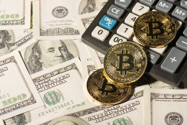 Photo aérienne de la crypto-monnaie bitcoin en or avec calculatrice isolée sur fond de dollars