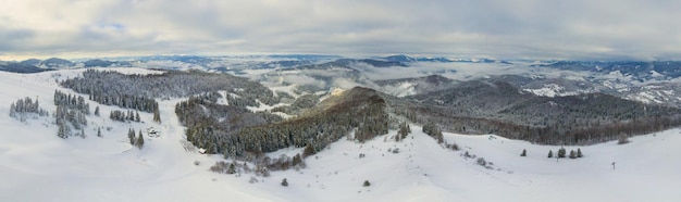 Photo aérienne du lever de soleil majestueux dans les montagnes La vallée entre les montagnes est couverte de brouillard et est éclairée par les rayons chauds du soleil levant Montagnes couvertes de forêt naturelle