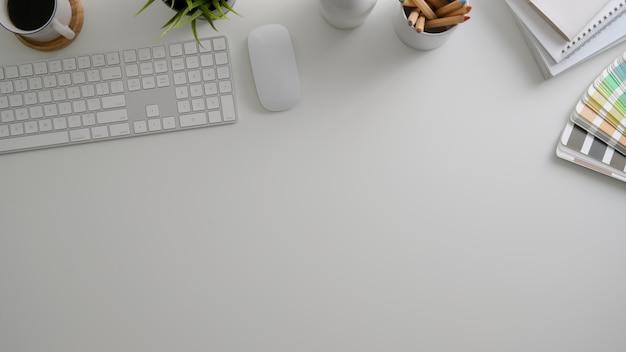 Photo aérienne d'un espace de travail minimaliste avec ordinateur, fournitures de bureau, nuancier de couleurs et espace de copie